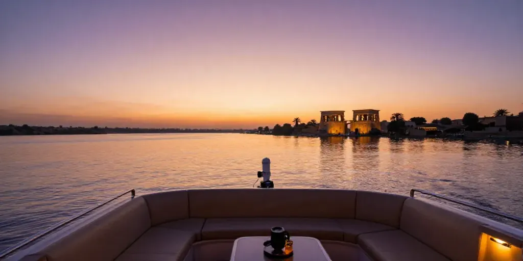 Experience a serene Lake Nasser Cruise at sunset, passengers enjoy the beautiful view with ancient temples in the background.